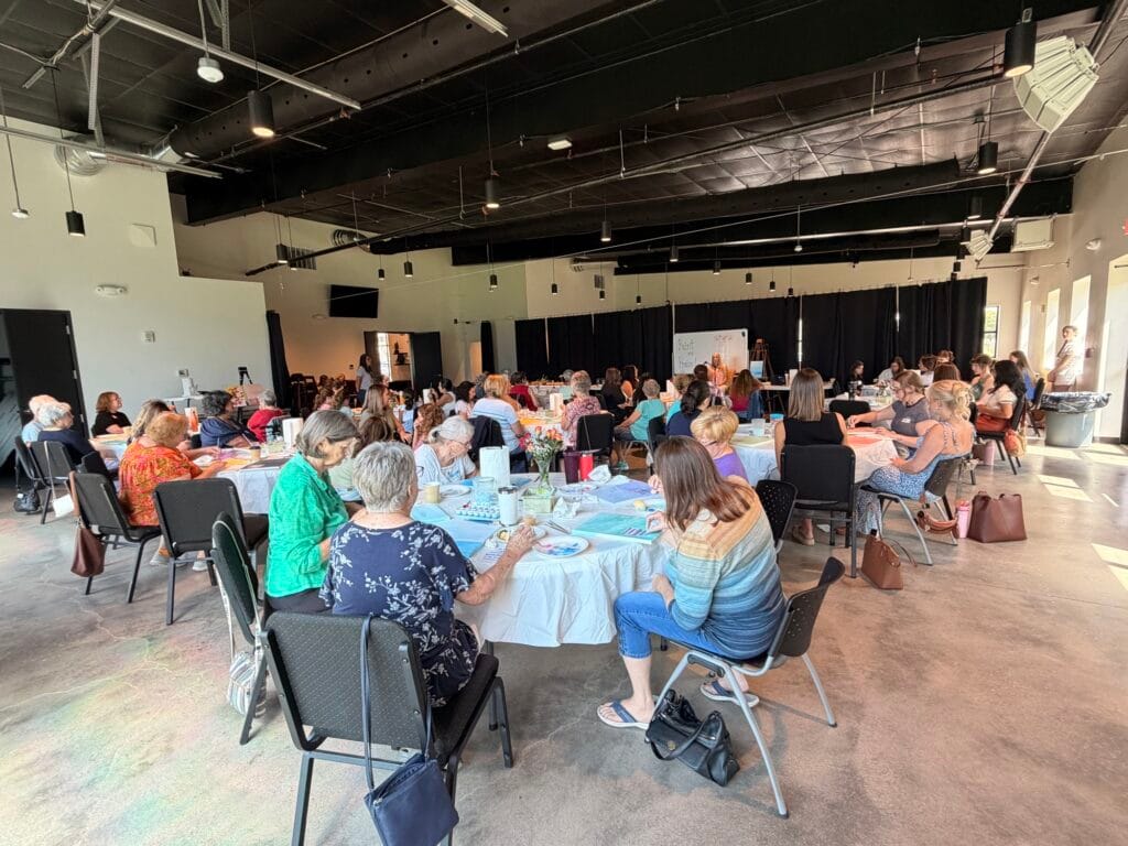 A large group gathered around tables for a class discussion at Community Baptist Church